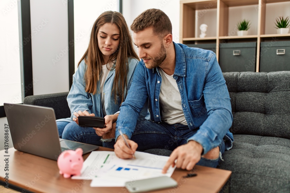Young caucasian couple controlling family economy at home. Young caucasian couple controlling family economy at home.