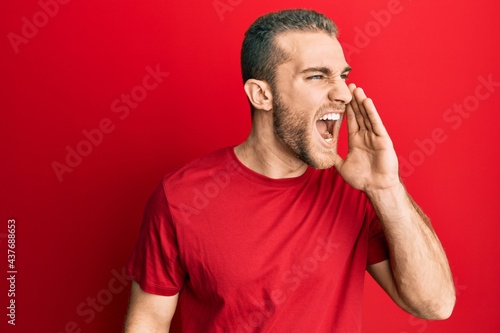 Young caucasian man wearing casual clothes shouting and screaming loud to side with hand on mouth. communication concept.