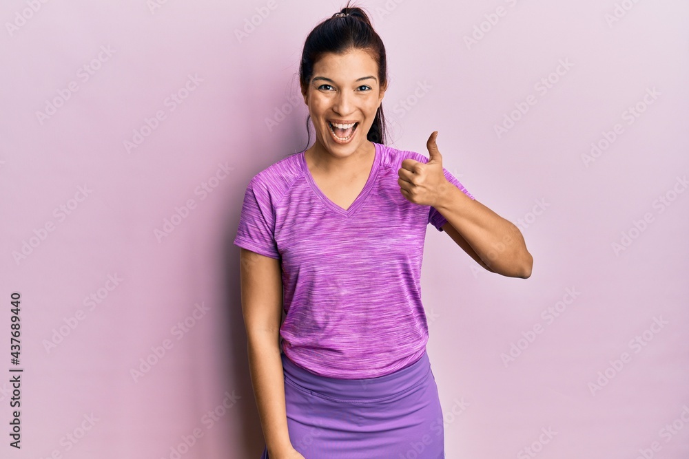 Young latin woman wearing sportswear smiling happy and positive, thumb up doing excellent and approval sign Young latin woman wearing sportswear smiling happy and positive, thumb up doing excellent and approval sign