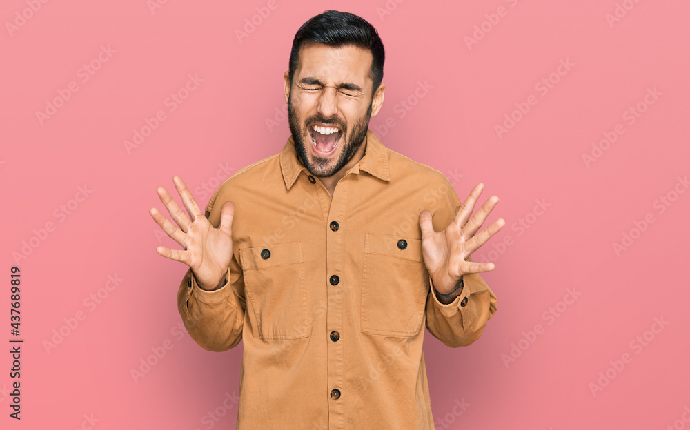 Fototapeta premium Young hispanic man wearing casual clothes celebrating mad and crazy for success with arms raised and closed eyes screaming excited. winner concept