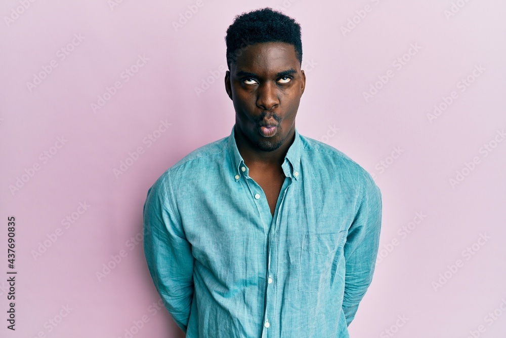 Handsome black man wearing casual clothes making fish face with lips, crazy and comical gesture. funny expression.