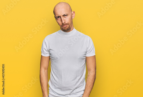 Bald man with beard wearing casual white t shirt skeptic and nervous, frowning upset because of problem. negative person.