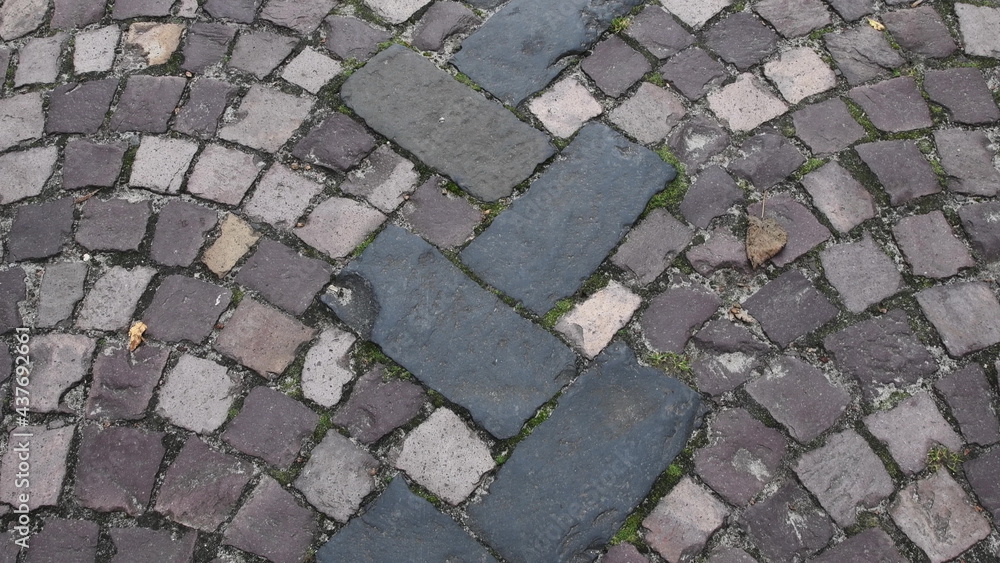 Ancient stone paving road in old town. Cobblestone pavement with rectangular and semicircular stone patterns. Roman road texture with dry fall leaves Ancient stone paving road in old town. Cobblestone pavement with rectangular and semicircular stone patterns. Roman road texture with dry fall leaves