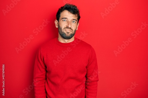 Handsome man with beard wearing casual red sweater looking sleepy and tired, exhausted for fatigue and hangover, lazy eyes in the morning. © Krakenimages.com
