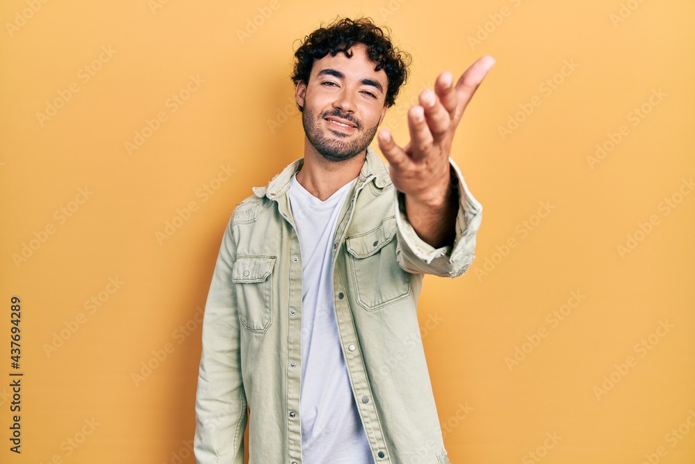 Young hispanic man wearing casual clothes smiling friendly offering handshake as greeting and welcoming. successful business. Young hispanic man wearing casual clothes smiling friendly offering handshake as greeting and welcoming. successful business.
