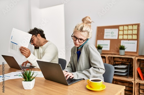 Two business workers talking on the smartphone and using laptop at the office.