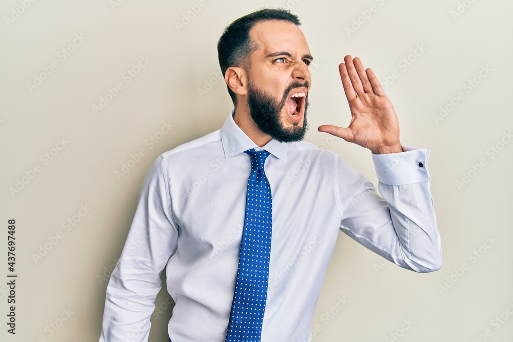 Young man with beard wearing business tie shouting and screaming loud to side with hand on mouth. communication concept. Young man with beard wearing business tie shouting and screaming loud to side with hand on mouth. communication concept.
