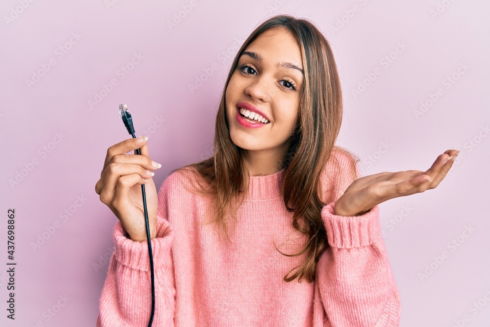 Young brunette woman holding ethernet rj45 cable celebrating achievement with happy smile and winner expression with raised hand Young brunette woman holding ethernet rj45 cable celebrating achievement with happy smile and winner expression with raised hand