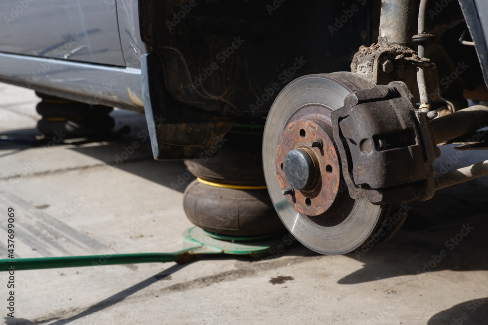 Car repair. Car with removed wheels on pneumatic jacks. View of the brake discs hub. Car repair. Car with removed wheels on pneumatic jacks. View of the brake discs hub.