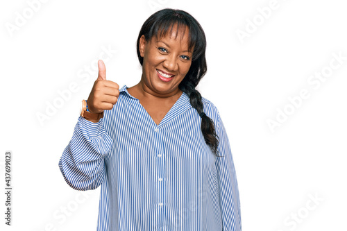 Hispanic middle age woman wearing casual clothes smiling happy and positive, thumb up doing excellent and approval sign