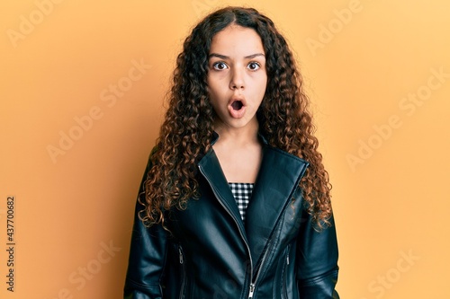 Teenager hispanic girl wearing black leather jacket scared and amazed with open mouth for surprise, disbelief face