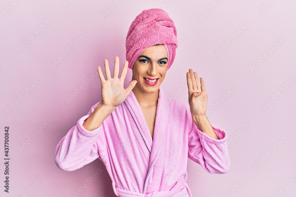 Young man wearing woman make up wearing shower towel on head and bathrobe showing and pointing up with fingers number nine while smiling confident and happy. Young man wearing woman make up wearing shower towel on head and bathrobe showing and pointing up with fingers number nine while smiling confident and happy.
