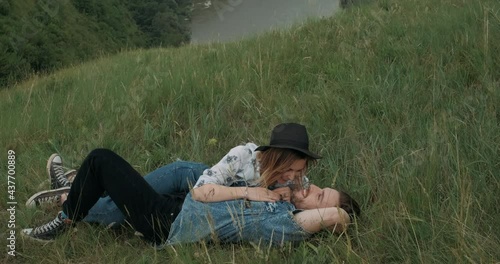 Wallpaper Mural Young Stylish Couple, Long Haired Man and Woman with Hat Dressed in Boho Style, Having Fun While Lying on Grass on Top of Hill, Canyon River on Background, Camera Moves Towards to Models Torontodigital.ca