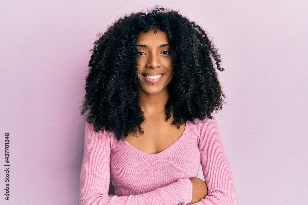 African american woman with afro hair wearing casual pink shirt happy face smiling with crossed arms looking at the camera. positive person. African american woman with afro hair wearing casual pink shirt happy face smiling with crossed arms looking at the camera. positive person.