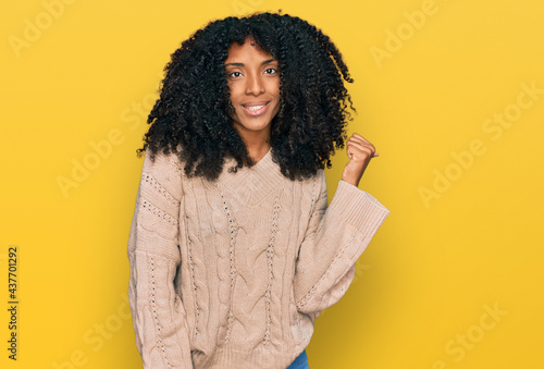 Young african american girl wearing casual clothes smiling with happy face looking and pointing to the side with thumb up.