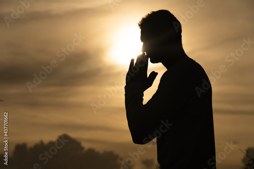 Silhouette of Man pray on during sunset. Religion, faith and hope concept 