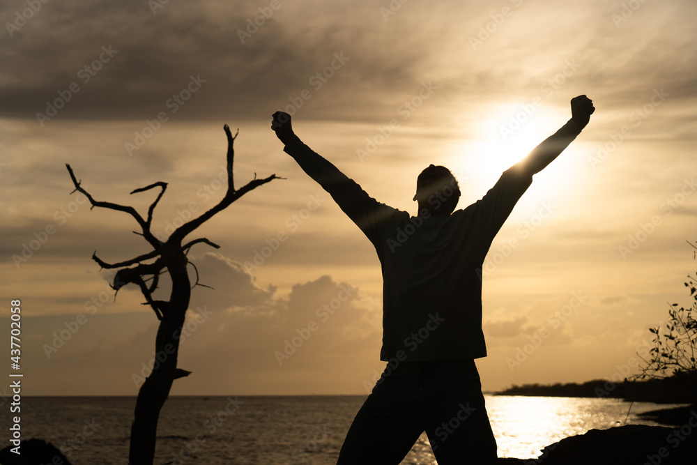Fototapeta premium Happy exited Man Jumping on sea and Beautiful Sunrise background. Happiness, joy and success concept