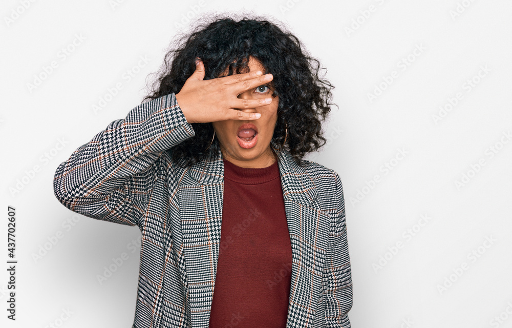 Young hispanic woman wearing business clothes peeking in shock covering face and eyes with hand, looking through fingers with embarrassed expression. Young hispanic woman wearing business clothes peeking in shock covering face and eyes with hand, looking through fingers with embarrassed expression.