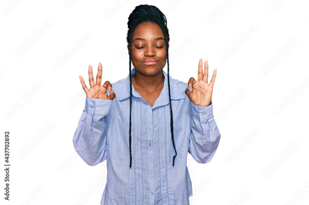 Young african american woman wearing casual clothes relax and smiling with eyes closed doing meditation gesture with fingers. yoga concept. Young african american woman wearing casual clothes relax and smiling with eyes closed doing meditation gesture with fingers. yoga concept.