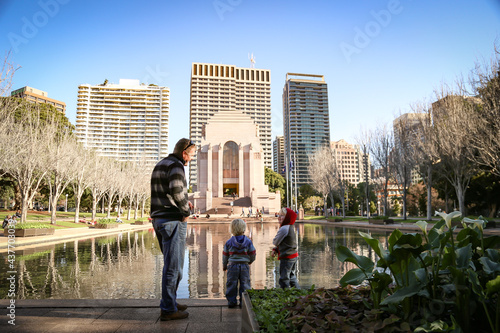 Father and sons enjoying quality time together standing in front of the Pool of Reflections Anzac War Memorial in Hyde Park, Sydney Australia