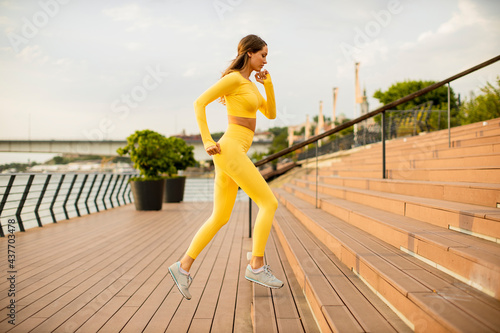 Young woman running on the stairs at the riverside photo