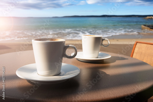 Two cups of coffee on a table at the beach. Atmospheric mediterranean vacation photography with a beautiful sea view.