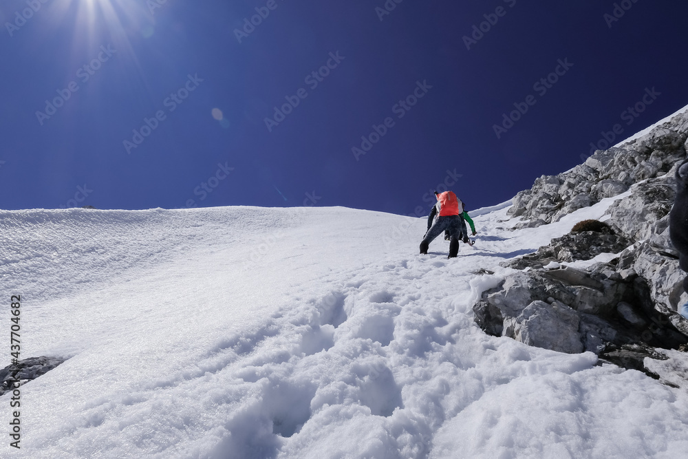 mountaineers with ice axes climb a sheer ice wall on a snowy alpine slope