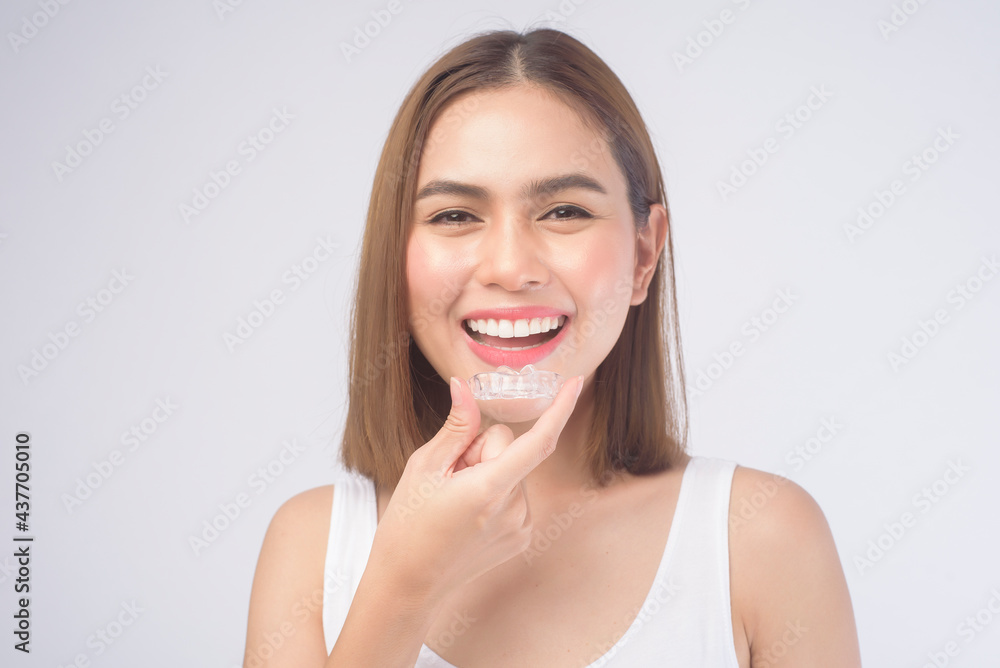Young smiling woman holding invisalign braces over white background studio, dental healthcare and Orthodontic concept. Young smiling woman holding invisalign braces over white background studio, dental healthcare and Orthodontic concept.