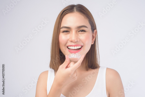 Young smiling woman holding invisalign braces over white background studio, dental healthcare and Orthodontic concept. photo