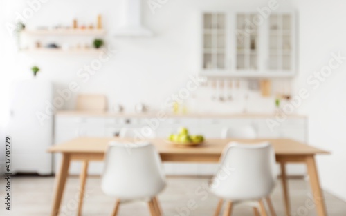 Comfortable light kitchen and stylish cozy design. Blurred background with wooden dining table and chairs