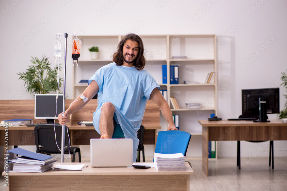 Young sick male employee in blood transfusion concept