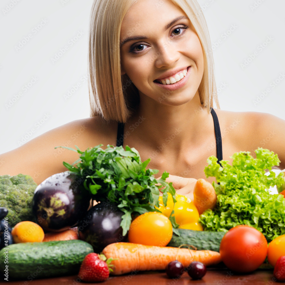 Portrait of happy smiling young beautiful blond woman with healthy vegetarian food, isolated over grey background. Girl in dieting, loss weight and healthy eating concept. Square. Portrait of happy smiling young beautiful blond woman with healthy vegetarian food, isolated over grey background. Girl in dieting, loss weight and healthy eating concept. Square.