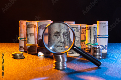 Money through a magnifying glass. Banknotes and coins on the table. Low key. photo