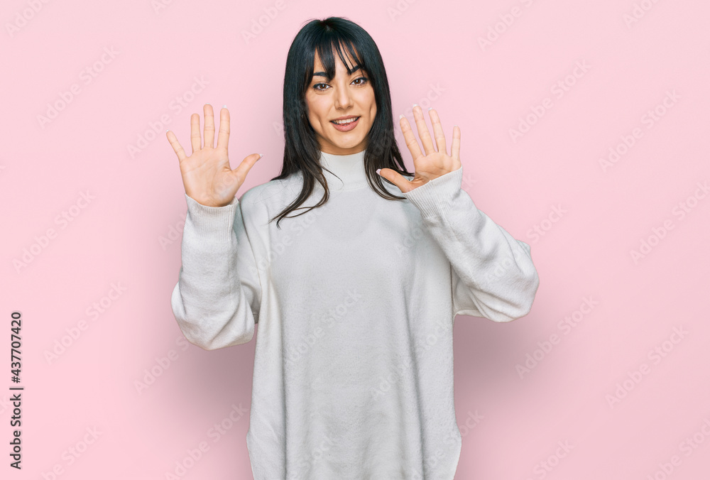 Young brunette woman with bangs wearing casual turtleneck sweater showing and pointing up with fingers number ten while smiling confident and happy. Young brunette woman with bangs wearing casual turtleneck sweater showing and pointing up with fingers number ten while smiling confident and happy.