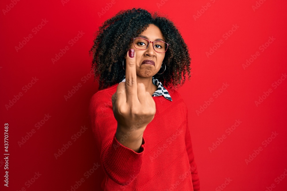 Beautiful african american woman with afro hair wearing sweater and glasses showing middle finger, impolite and rude fuck off expression Beautiful african american woman with afro hair wearing sweater and glasses showing middle finger, impolite and rude fuck off expression