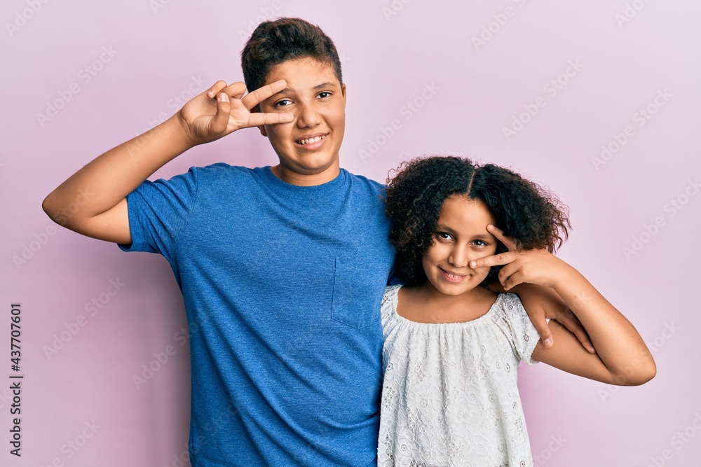 Obraz premium Young hispanic family of brother and sister wearing casual clothes together doing peace symbol with fingers over face, smiling cheerful showing victory