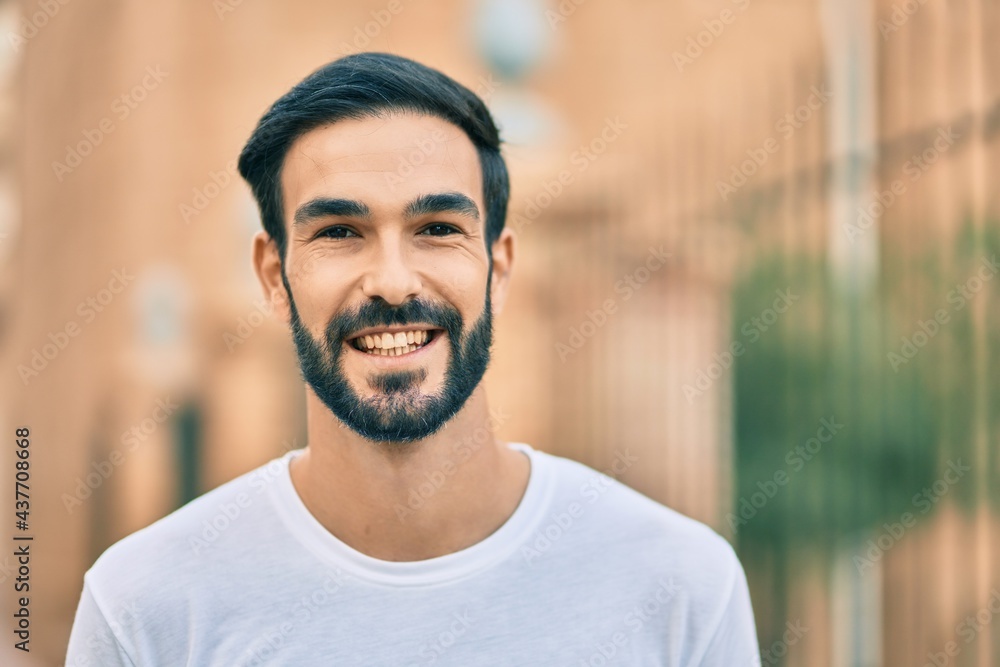 Young hispanic man smiling happy standing at the city.