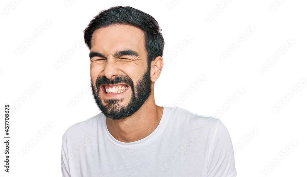 Young hispanic man wearing casual white t shirt very happy and excited doing winner gesture with arms raised, smiling and screaming for success. celebration concept. Young hispanic man wearing casual white t shirt very happy and excited doing winner gesture with arms raised, smiling and screaming for success. celebration concept.