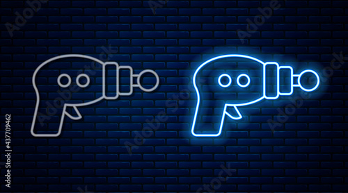 Glowing neon line Ray gun icon isolated on brick wall background. Laser weapon. Space blaster. Vector