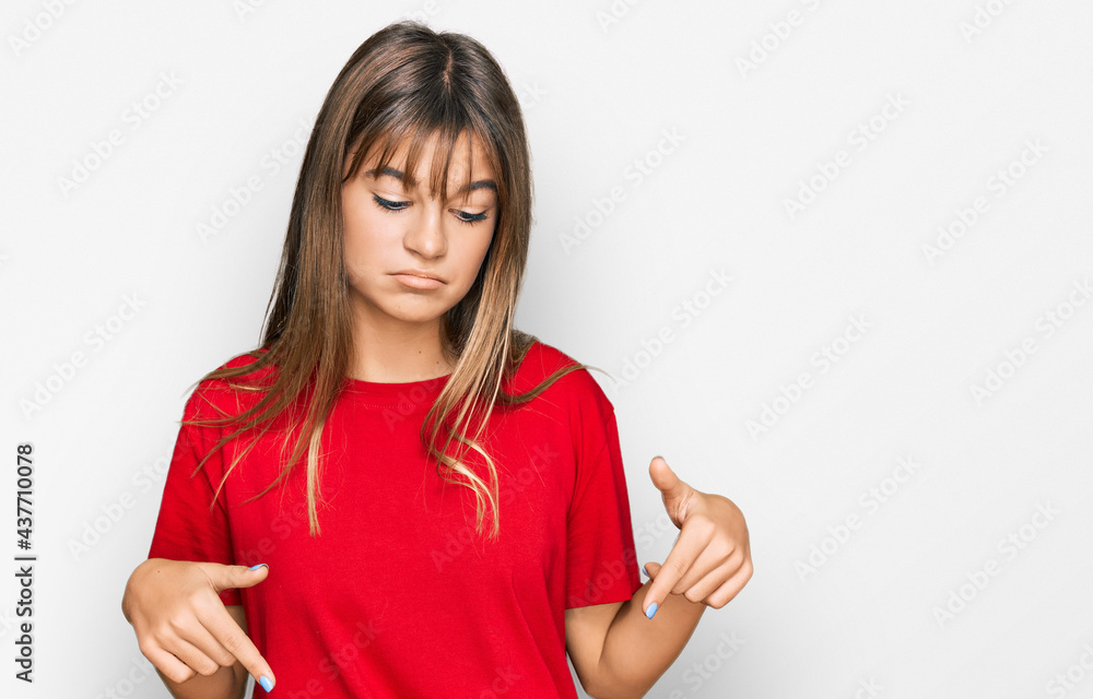 Teenager caucasian girl wearing casual red t shirt pointing down looking sad and upset, indicating direction with fingers, unhappy and depressed. Teenager caucasian girl wearing casual red t shirt pointing down looking sad and upset, indicating direction with fingers, unhappy and depressed.