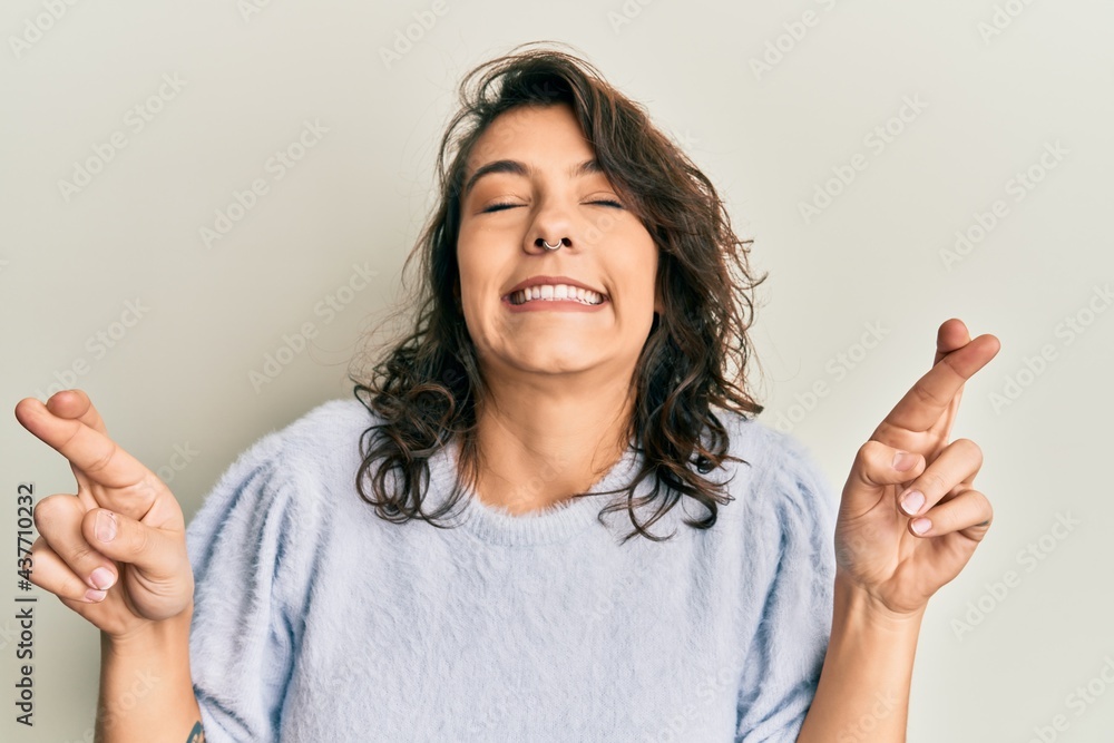Young hispanic woman wearing casual winter sweater gesturing finger crossed smiling with hope and eyes closed. luck and superstitious concept. Young hispanic woman wearing casual winter sweater gesturing finger crossed smiling with hope and eyes closed. luck and superstitious concept.