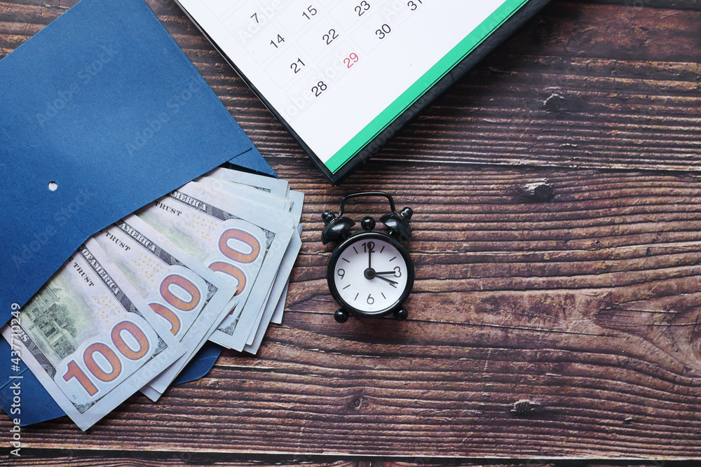 Close up of cash in a envelope , calendar and old clock on table Close up of cash in a envelope , calendar and old clock on table