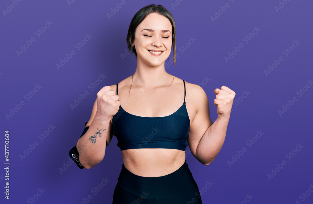Young hispanic woman wearing sportswear excited for success with arms raised and eyes closed celebrating victory smiling. winner concept. Young hispanic woman wearing sportswear excited for success with arms raised and eyes closed celebrating victory smiling. winner concept.