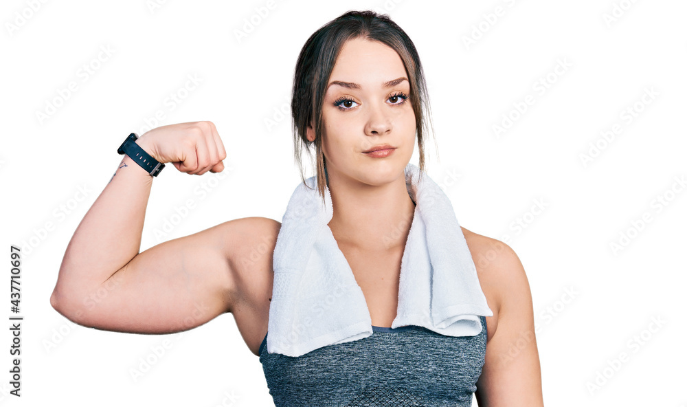 Young hispanic girl wearing sportswear and towel strong person showing arm muscle, confident and proud of power Young hispanic girl wearing sportswear and towel strong person showing arm muscle, confident and proud of power