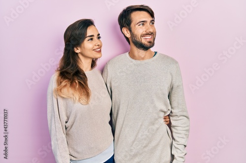 Young hispanic couple wearing casual clothes looking away to side with smile on face, natural expression. laughing confident.