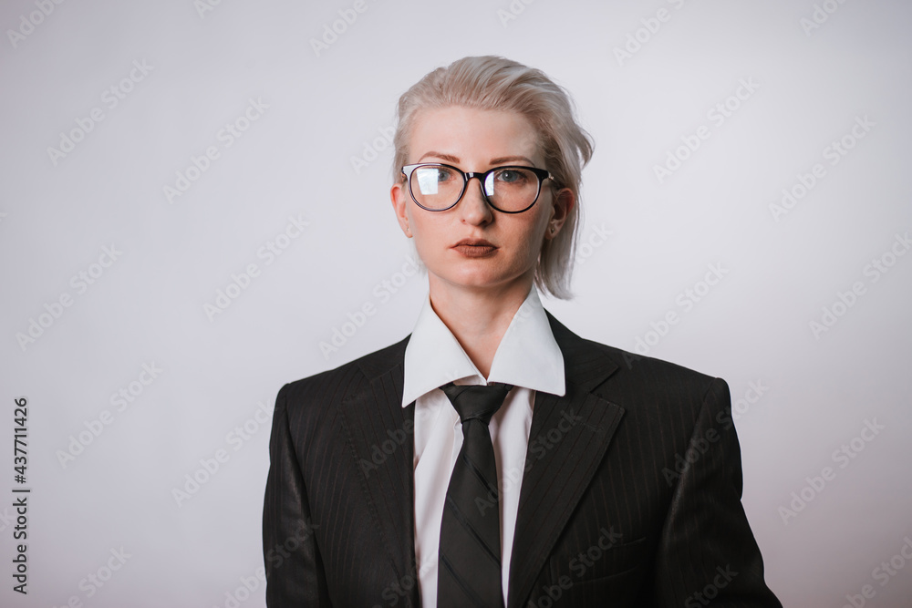Fashionable portrait of a woman dressed in men's clothing. Girl in a white shirt, jacket and tie on a white background. The idea of a strong woman as a man. Fashionable portrait of a woman dressed in men's clothing. Girl in a white shirt, jacket and tie on a white background. The idea of a strong woman as a man.
