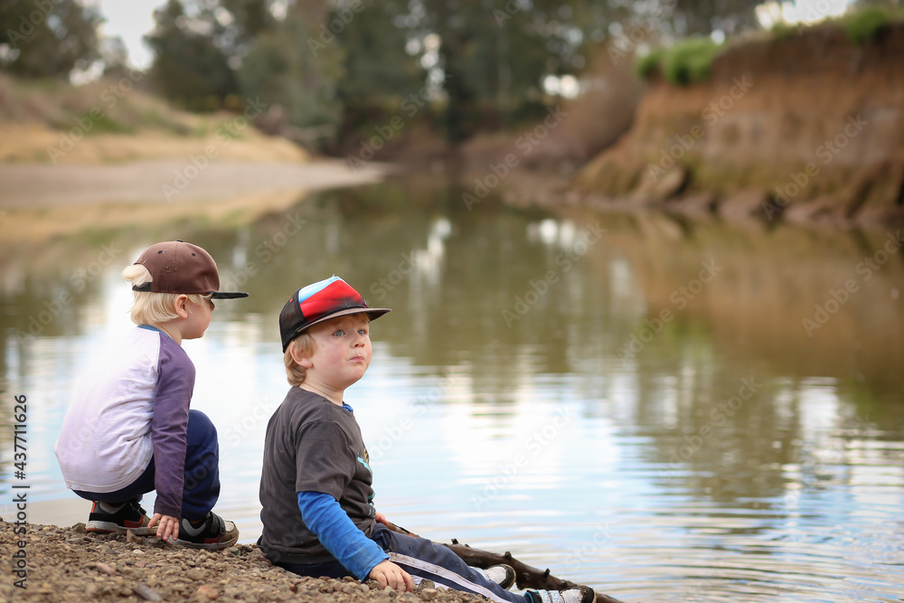 Little boys sitting on rivers edge in Gunnedah, NSW Australia Little boys sitting on rivers edge in Gunnedah, NSW Australia