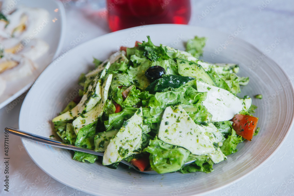 Caesar salad of herbs, cheese and olives on a white plate.