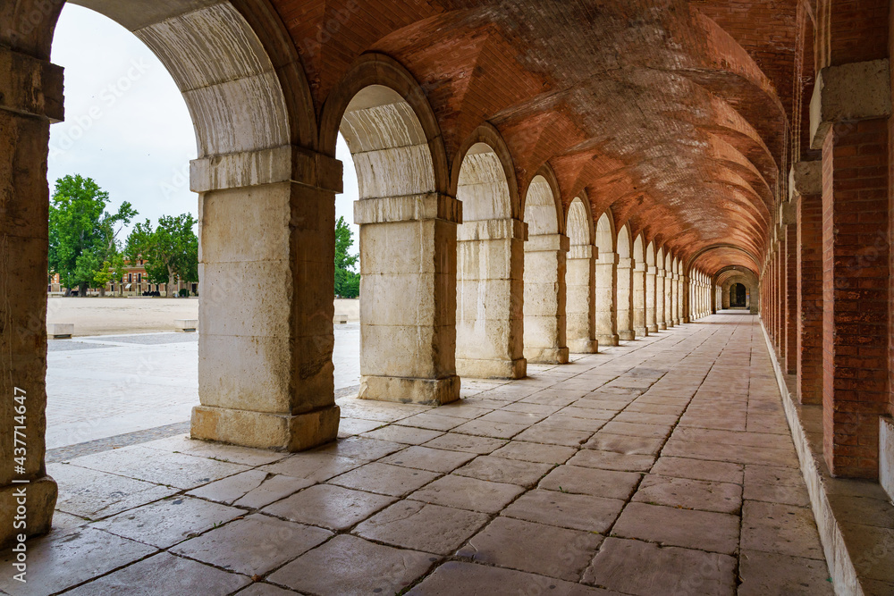 Large symmetrical exterior corridor with arches and columns in the old royal palace of Aranjuez.