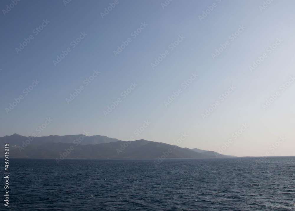 Distant land in the ocean, tranquil calm water, beautiful blue ocean and blue sky, travel destination, summertime season, vacation in the nature